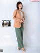 A woman in a beige blazer and green pants.