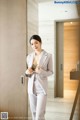 A woman in a white suit standing in front of a mirror.