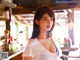 A woman in a white shirt standing in front of a bar.