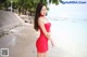 A woman in a red dress standing on a beach.